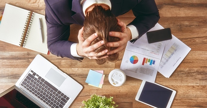 businessman in panic. a young man sits at his Desk and holds his hands on his head.