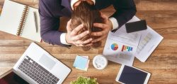 businessman in panic. a young man sits at his Desk and holds his hands on his head.